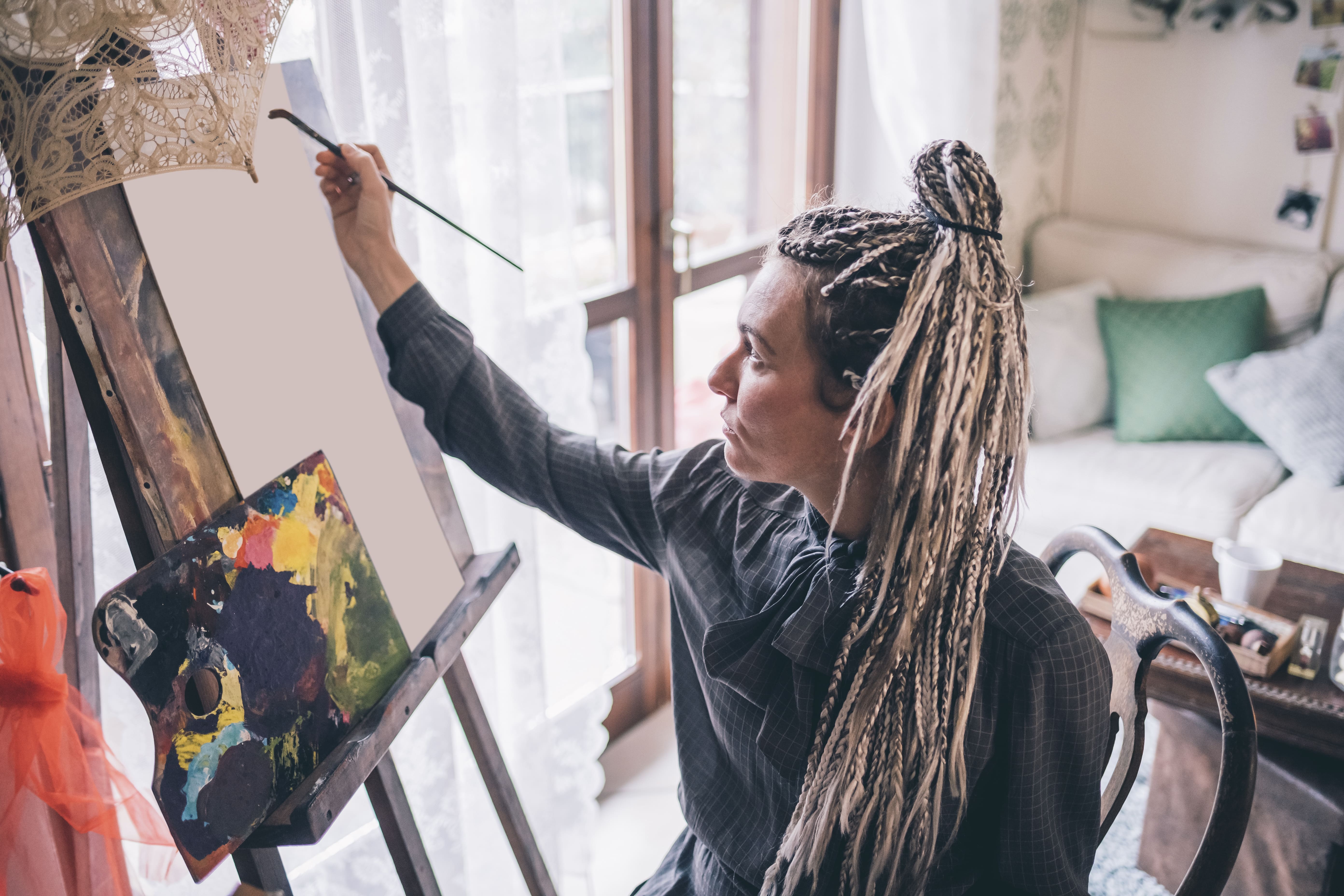 Primer plano de manos aplicando técnicas mixtas en una obra contemporánea, resaltando innovación artística y creatividad actual